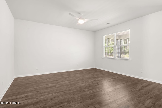 spare room featuring baseboards, dark wood finished floors, and ceiling fan