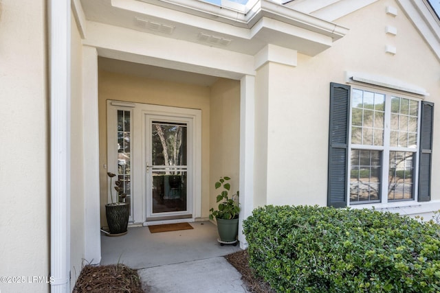 property entrance featuring visible vents and stucco siding