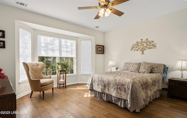 bedroom with wood finished floors, visible vents, and baseboards