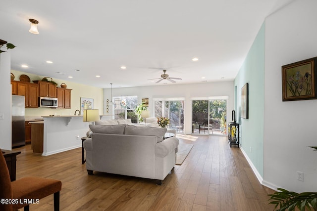 living area featuring baseboards, wood finished floors, a ceiling fan, and recessed lighting