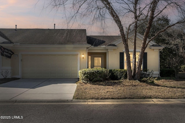 ranch-style house with a garage, concrete driveway, roof with shingles, and stucco siding