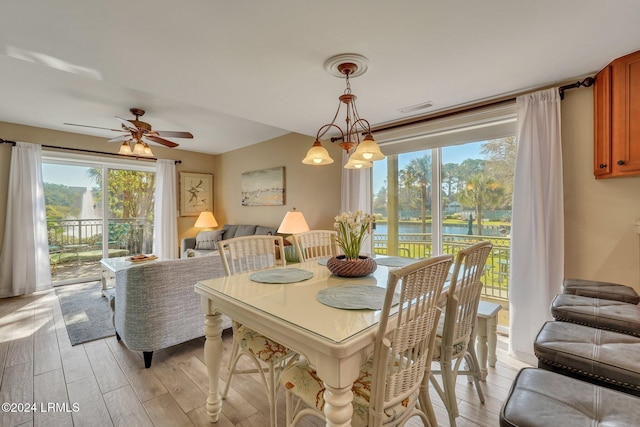 dining area featuring a water view, ceiling fan with notable chandelier, and light hardwood / wood-style flooring