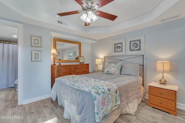 bedroom featuring a raised ceiling, ceiling fan, and light hardwood / wood-style flooring