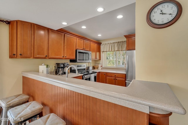 kitchen with appliances with stainless steel finishes, a breakfast bar area, and kitchen peninsula