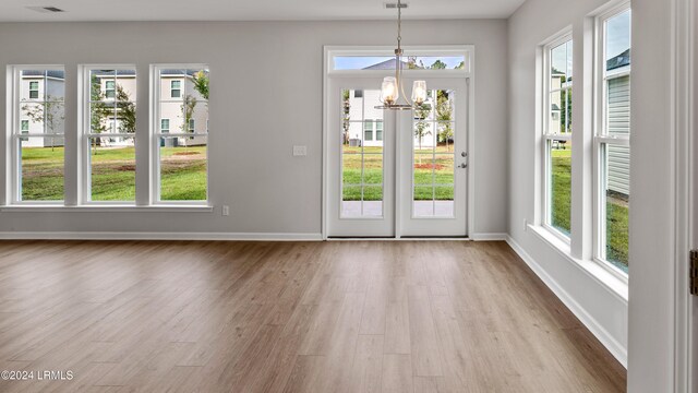 doorway featuring an inviting chandelier, a wealth of natural light, and light hardwood / wood-style flooring