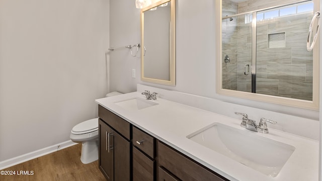 bathroom featuring vanity, hardwood / wood-style floors, a shower with shower door, and toilet