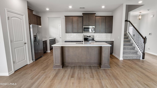 kitchen featuring tasteful backsplash, appliances with stainless steel finishes, dark brown cabinets, and light wood-type flooring