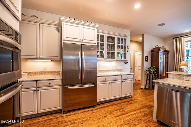 kitchen featuring appliances with stainless steel finishes, light stone countertops, and light hardwood / wood-style floors