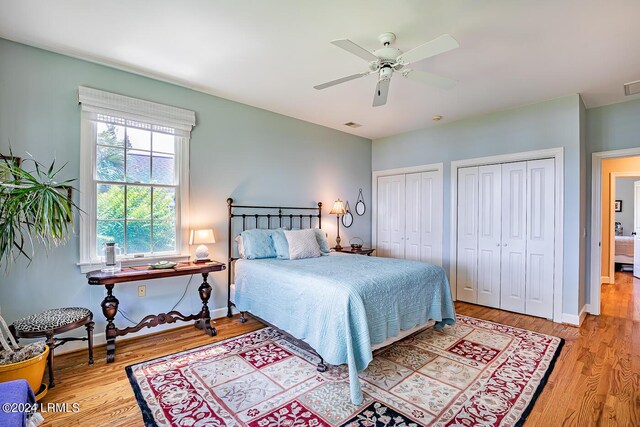 bedroom featuring multiple closets, ceiling fan, and light hardwood / wood-style flooring