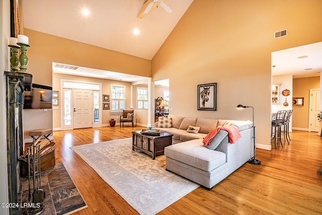 living room featuring ceiling fan, high vaulted ceiling, and light hardwood / wood-style flooring