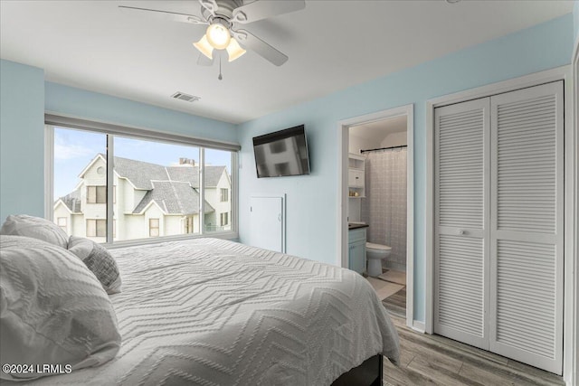 bedroom with hardwood / wood-style flooring, ceiling fan, connected bathroom, and a closet