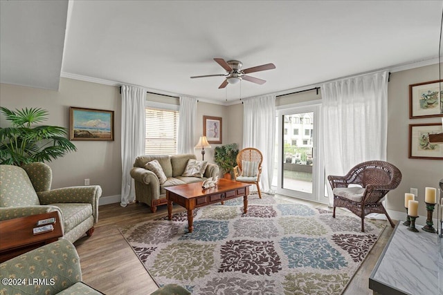 living room featuring wood-type flooring, ornamental molding, and ceiling fan