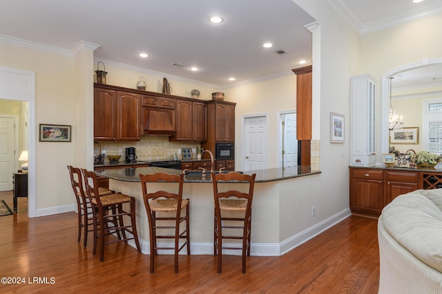 34 Osprey Cir, Okatie, SC 29909 - kitchen with a breakfast bar, hardwood / wood-style floors, dark stone countertops, kitchen peninsula, and custom range hood