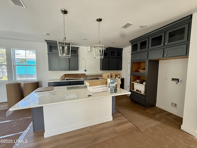 kitchen with a center island, light countertops, visible vents, and glass insert cabinets