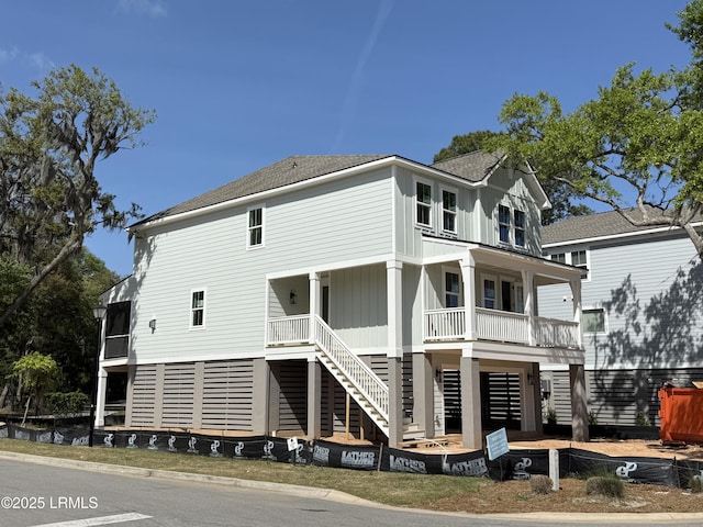 rear view of property featuring covered porch, roof with shingles, and stairway