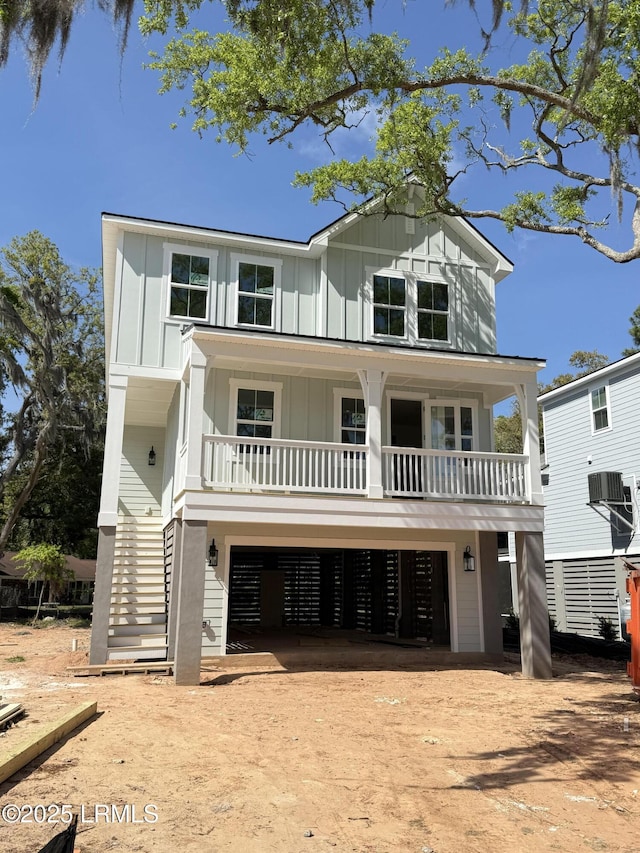 coastal home featuring dirt driveway, stairs, board and batten siding, covered porch, and a garage