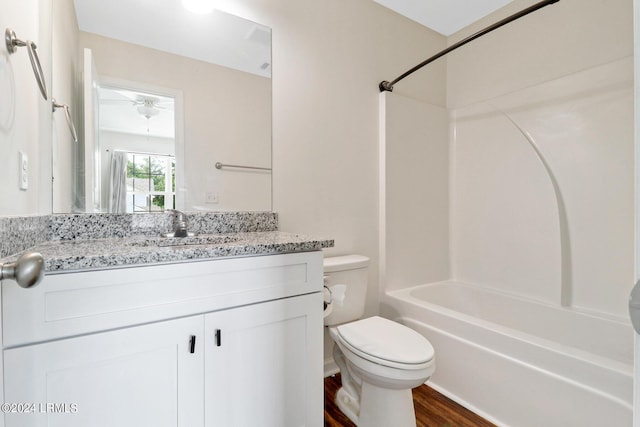 full bathroom featuring vanity, hardwood / wood-style floors, washtub / shower combination, and toilet