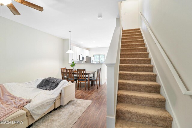 stairway with hardwood / wood-style flooring and ceiling fan