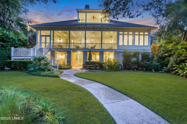 back of property with ceiling fan, stairs, a lawn, a sunroom, and a patio area