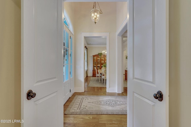 entrance foyer featuring baseboards, a notable chandelier, wood finished floors, and crown molding