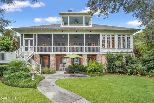 back of property featuring a yard, a patio, brick siding, and a sunroom