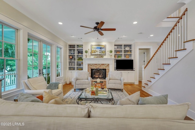 living room featuring built in features, stairs, recessed lighting, a fireplace, and wood finished floors