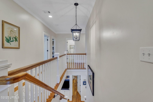 hallway featuring visible vents, light wood-style flooring, recessed lighting, ornamental molding, and an upstairs landing