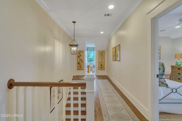 corridor featuring wood finished floors, visible vents, baseboards, recessed lighting, and ornamental molding