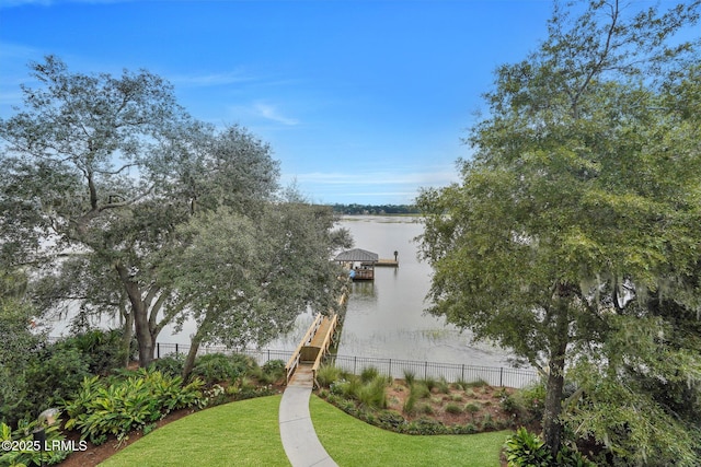 property view of water featuring fence and a boat dock