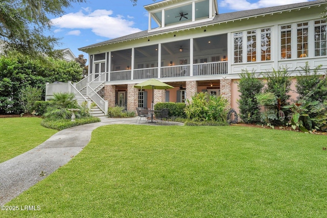 back of property with a yard, a patio area, brick siding, and a sunroom