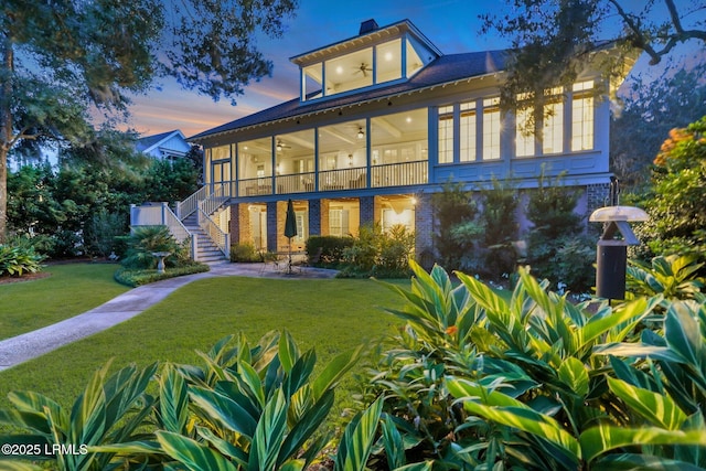 rear view of house featuring stairway, a lawn, a sunroom, a ceiling fan, and a patio