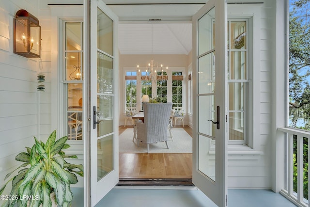 interior space with vaulted ceiling, a notable chandelier, french doors, and wood finished floors