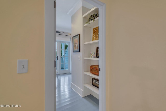 hall featuring built in shelves and wood finished floors