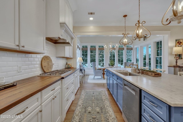 kitchen featuring appliances with stainless steel finishes, butcher block counters, blue cabinets, and a sink