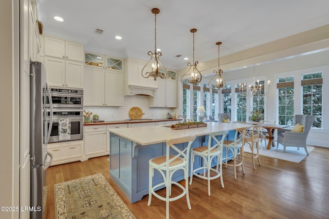 kitchen with decorative backsplash, visible vents, white cabinetry, and stainless steel appliances