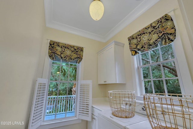 kitchen featuring white cabinetry, light countertops, ornamental molding, a wealth of natural light, and washer / clothes dryer