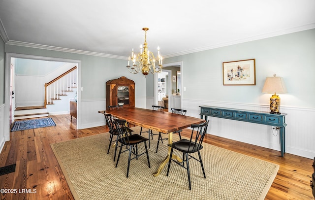 79 Lost Island Rd, Beaufort, SC 29907 - dining area featuring ornamental molding, a chandelier, a wainscoted wall, stairs, and wood finished floors