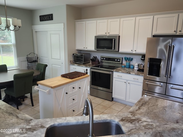 125 Pleasant Point Dr, Beaufort, SC 29907 - kitchen featuring appliances with stainless steel finishes, a sink, white cabinetry, and a chandelier