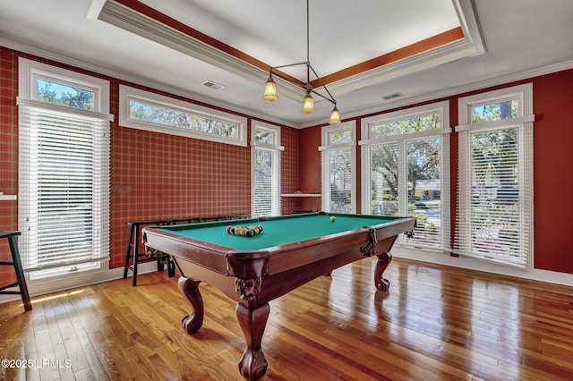 recreation room featuring ornamental molding, hardwood / wood-style floors, a raised ceiling, and a wealth of natural light