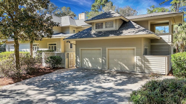 view of front of house with a garage, roof with shingles, and driveway