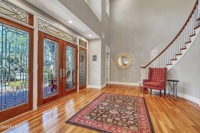 foyer featuring stairway, wood-type flooring, a high ceiling, and baseboards