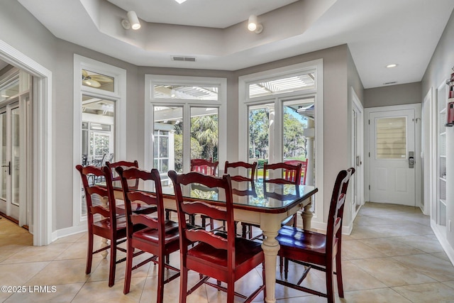 dining room with a tray ceiling, visible vents, baseboards, and light tile patterned floors