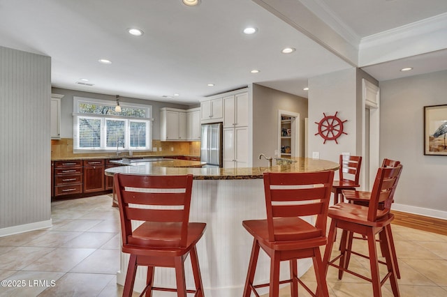 kitchen with decorative backsplash, freestanding refrigerator, stone countertops, and a breakfast bar area