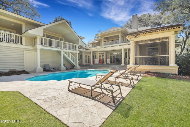 outdoor pool with a patio, stairway, and a lawn