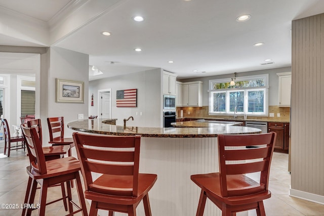 kitchen with appliances with stainless steel finishes, backsplash, and a kitchen breakfast bar