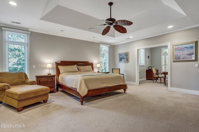 bedroom featuring ornamental molding, a tray ceiling, light carpet, and baseboards