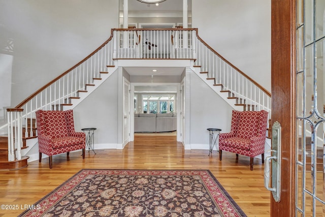 entrance foyer featuring stairs, a high ceiling, baseboards, and wood finished floors