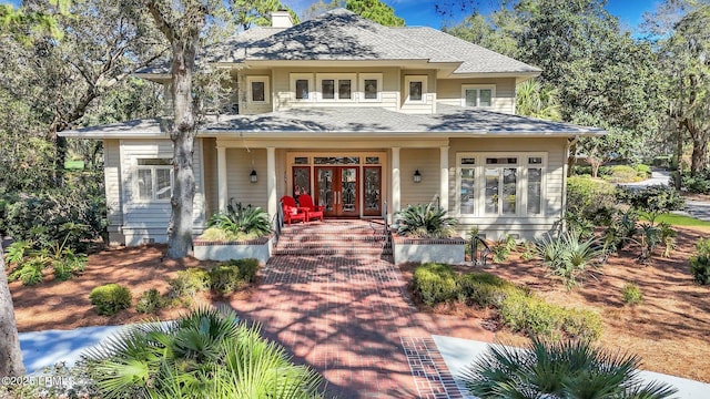 prairie-style home featuring a shingled roof, a chimney, and french doors