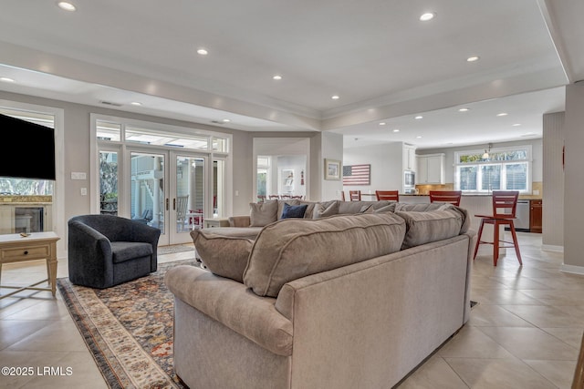 living room with light tile patterned floors, ornamental molding, a raised ceiling, and recessed lighting