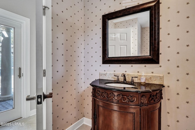 bathroom with wallpapered walls, tile patterned floors, baseboards, and vanity